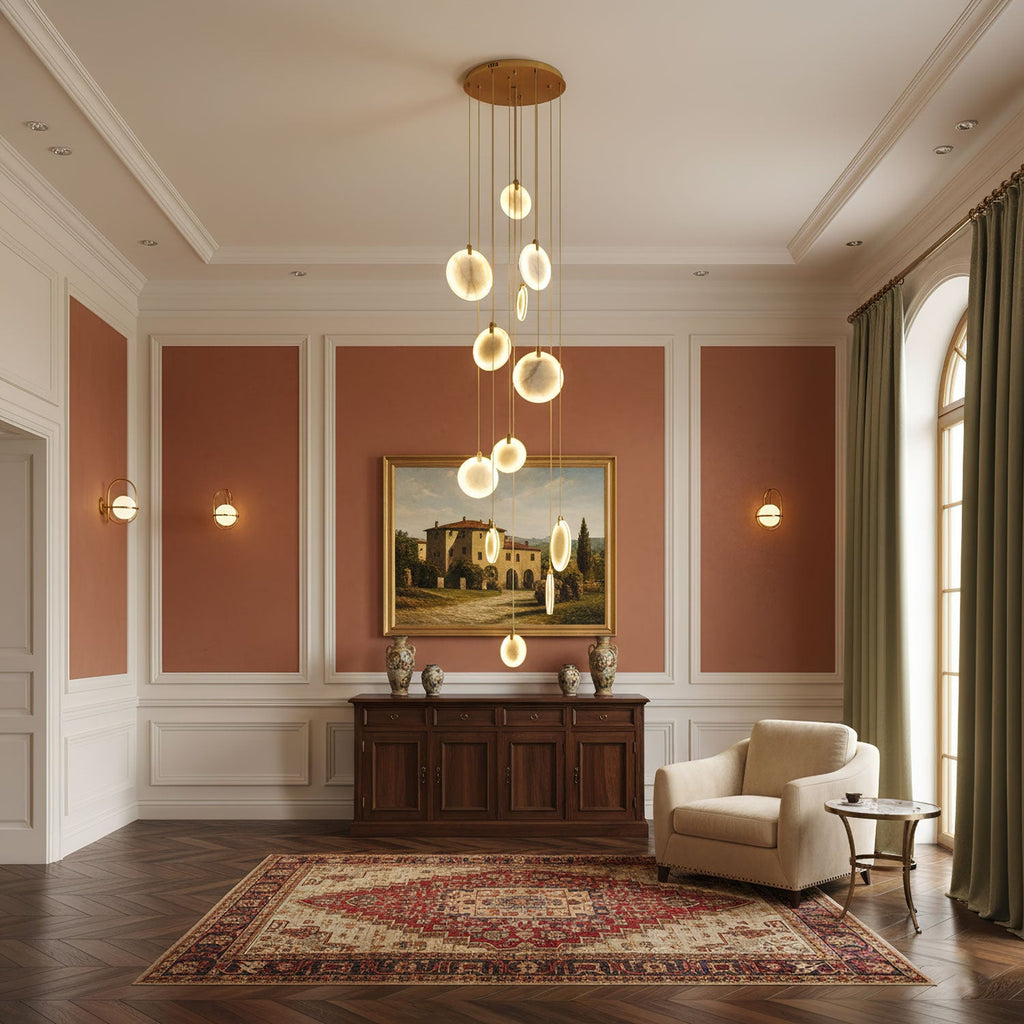 Clérachic alabaster disc pendants hang from a gold canopy in a room with terracotta wall panels, a landscape painting and a red rug.