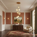 Clérachic alabaster disc pendants hang from a gold canopy in a room with terracotta wall panels, a landscape painting and a red rug.