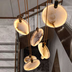 Close view from above of veined, lit alabaster discs on this Clérachic pendant, with a marble staircase and dark glass below.