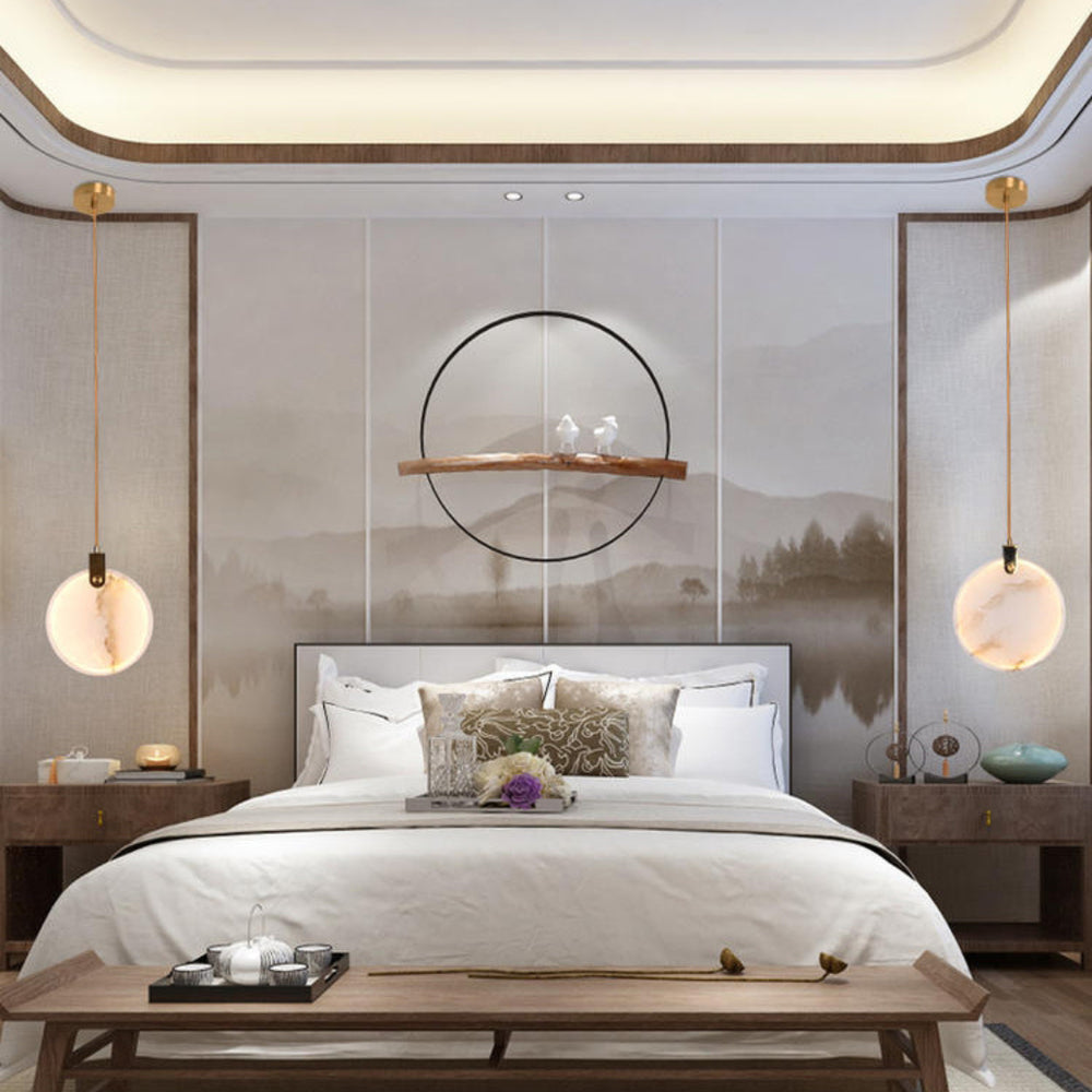 A Clérachic alabaster disc pendant hangs each side of a bed with a low bench at its foot, in front of a landscape mural.