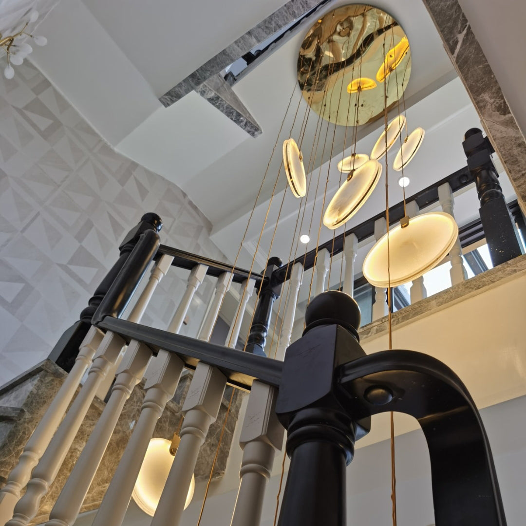 Looking up past a black and white balustrade, a Clérachic alabaster disc cluster hangs from a round, mirror-finish ceiling plate.