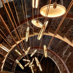 Looking up a spiral staircase of dark marble, edge-on Clérachic alabaster discs glow among long tan cords.
