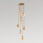 A Clérachic pendant cluster of seven alabaster discs at staggered heights from a gold canopy, on a soft grey backdrop.