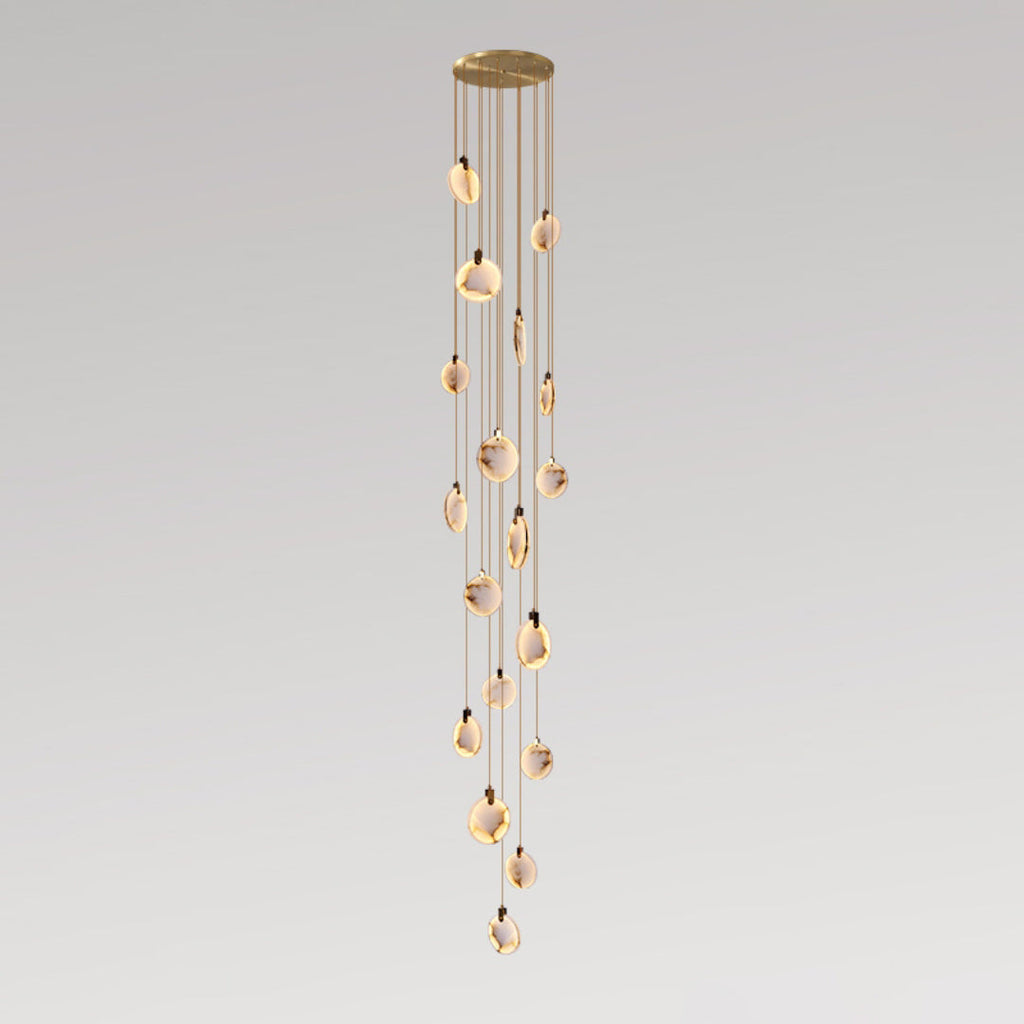 A long Clérachic pendant cluster with many small alabaster discs on tan cords, from a gold canopy, on a grey backdrop.