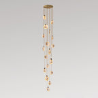 A long Clérachic pendant cluster with many small alabaster discs on tan cords, from a gold canopy, on a grey backdrop.