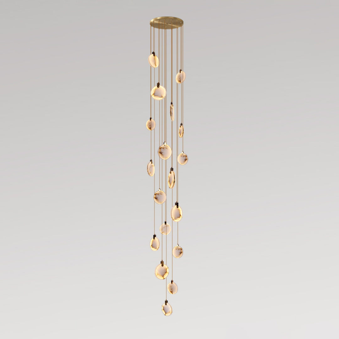 A long Clérachic pendant cluster with many small alabaster discs on tan cords, from a gold canopy, on a grey backdrop.