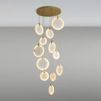 The same Clérachic alabaster discs lit up, glowing warm white at different heights from a round gold canopy on a grey backdrop.