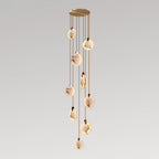 A Clérachic cluster of alabaster discs on tan cords in a loose column from a gold canopy, lit warm on a grey gradient backdrop.