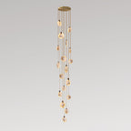 Very tall Clérachic cluster of small alabaster discs on tan cords, hanging from a gold canopy in a narrow column on grey.