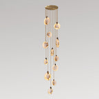 Clérachic alabaster disc pendants lit warm at staggered heights on tan cords from a round gold canopy, on a grey gradient backdrop.