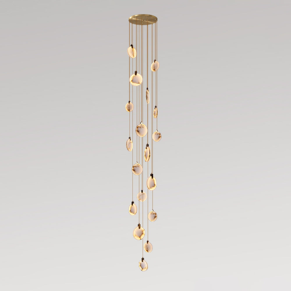 A very long column of small Clérachic alabaster discs on tan cords, lit warm and hanging from a gold canopy, on a grey backdrop.