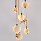 Close view of lit, veined alabaster discs hanging on tan cords from this Clérachic pendant, with dark hangers at the top of each.