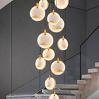 A Clérachic cluster of lit alabaster discs against a dark grey wall, with a glass balustrade and pale stone steps below.