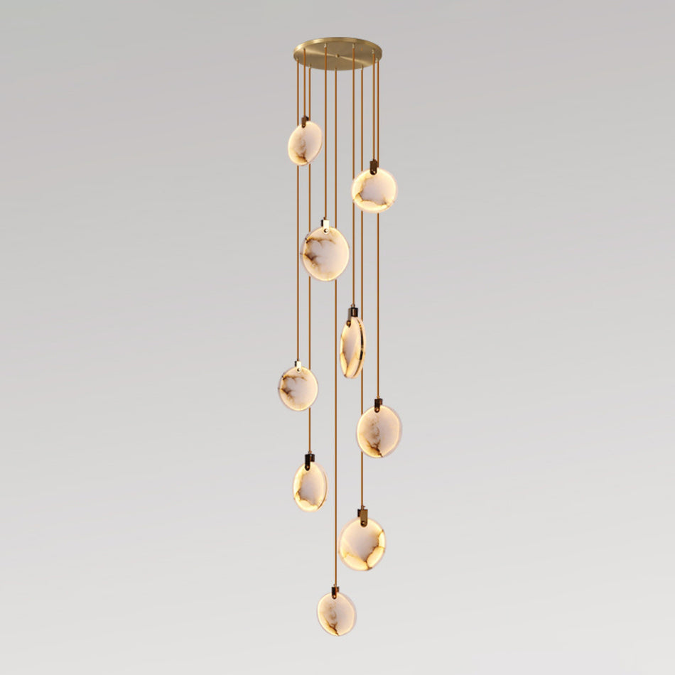A Clérachic pendant cluster of nine alabaster discs on thin tan cords from a gold canopy, lit warm on a grey gradient backdrop.