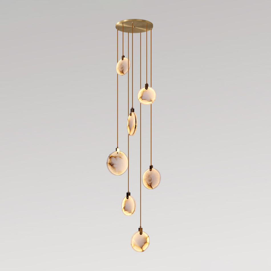 Seven alabaster discs of this Clérachic pendant hang at staggered lengths from a gold canopy, glowing against a pale backdrop.