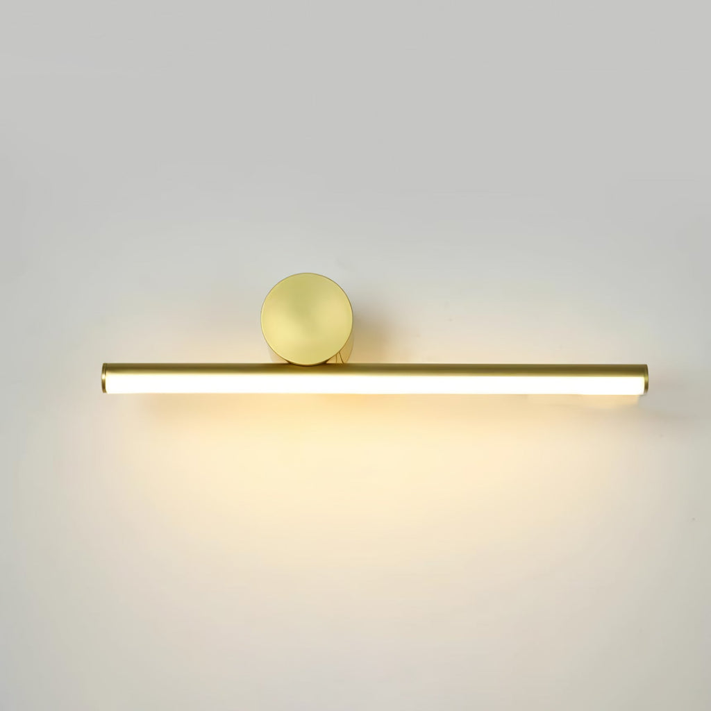 Horizontal gold tube of this Clérachic wall light with a round gold disc above it, lit with a warm glow on a pale wall.