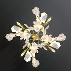 Angled view of the Clérachic gingko sconce, layered petal shades along gilded leaf-shaped arms.