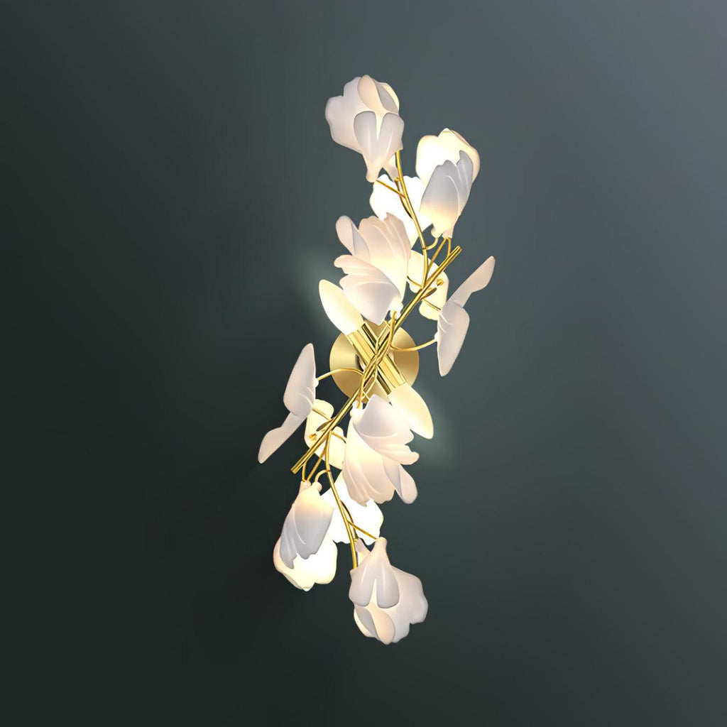 The Clérachic gingko sconce lit against a deep green wall, warm light washing through its white petals.