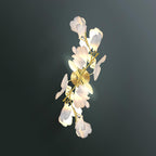 The Clérachic gingko sconce lit against a deep green wall, warm light washing through its white petals.