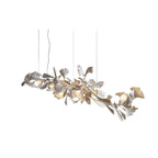 The Clérachic gingko chandelier stretched long on white, leaves lit along a horizontal branch.