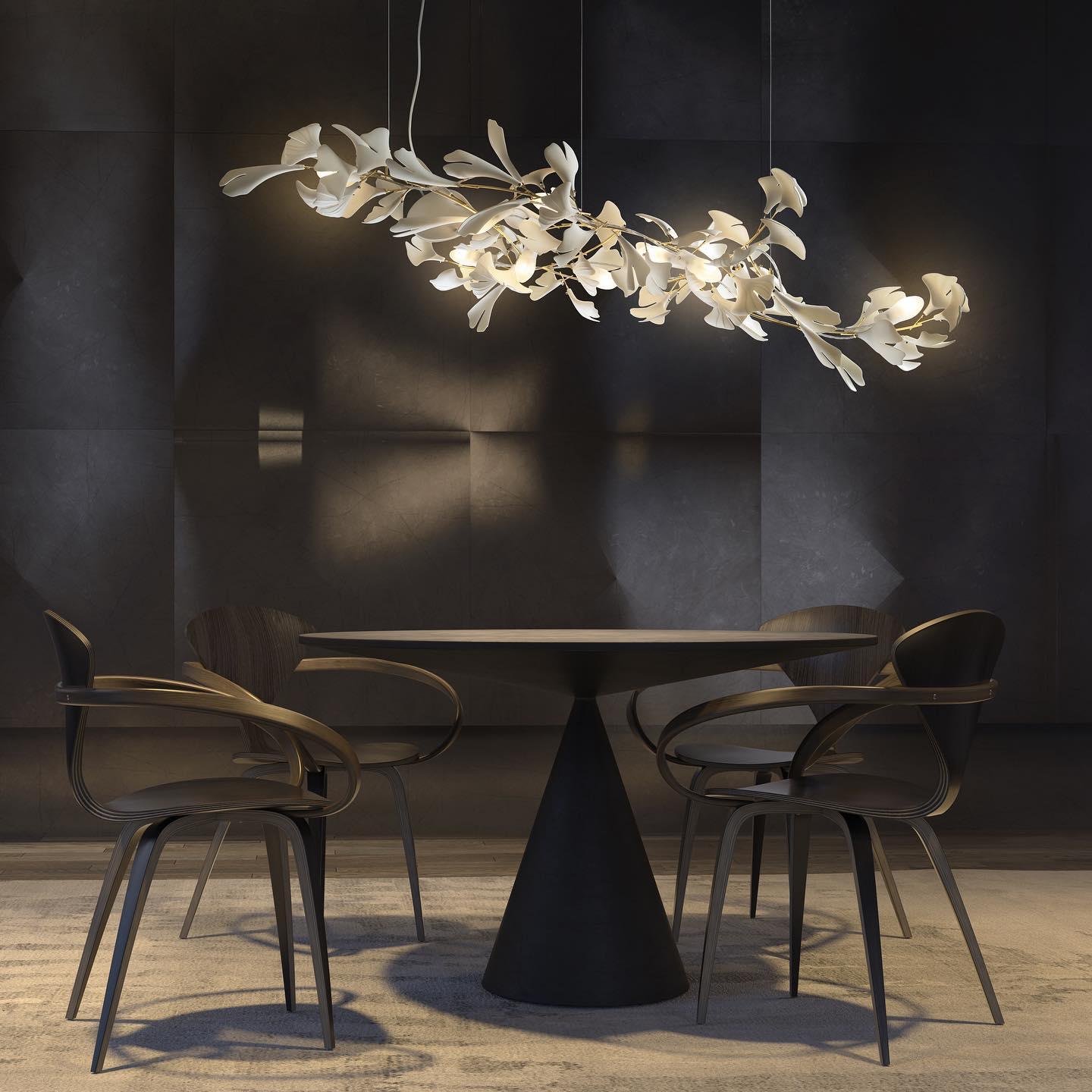 The Clérachic gingko chandelier lit above a round table with curved timber chairs in a dark room.