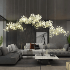The Clérachic gingko cluster chandelier lit above a grey sofa in a dark marble-walled living room.