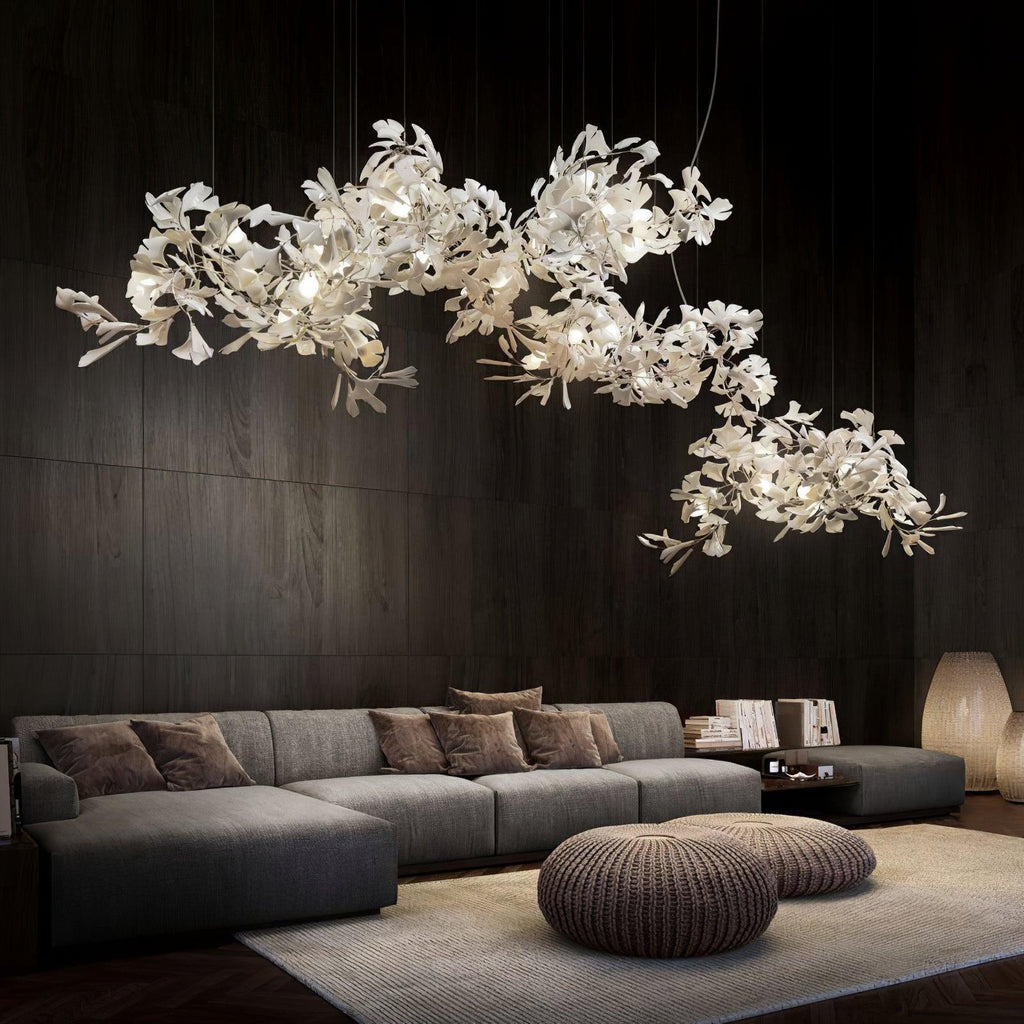 Clérachic gingko cluster chandelier lit above a long sofa against dark timber panelling.