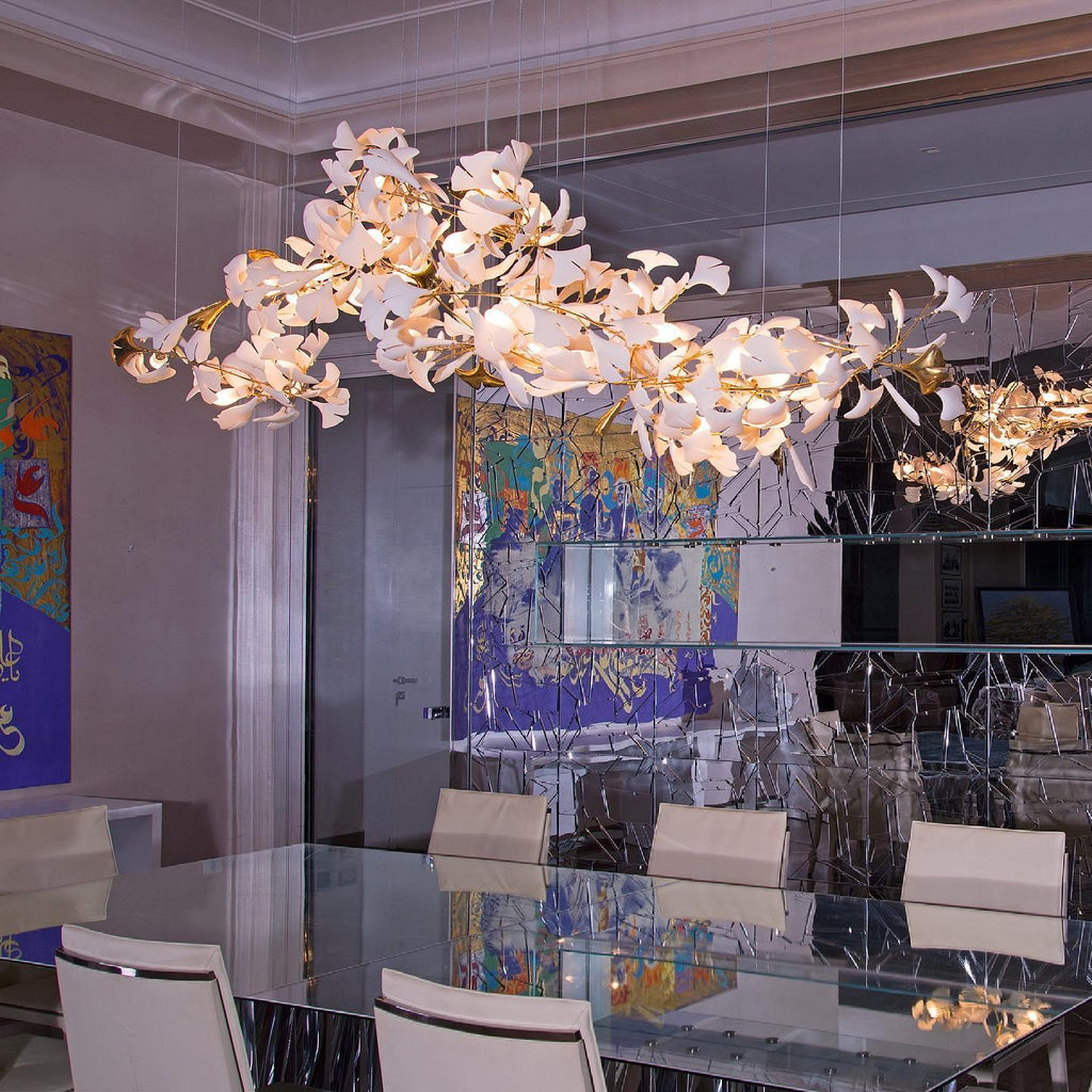 Clérachic gingko linear chandelier lit over a glass boardroom table beside a bright artwork.