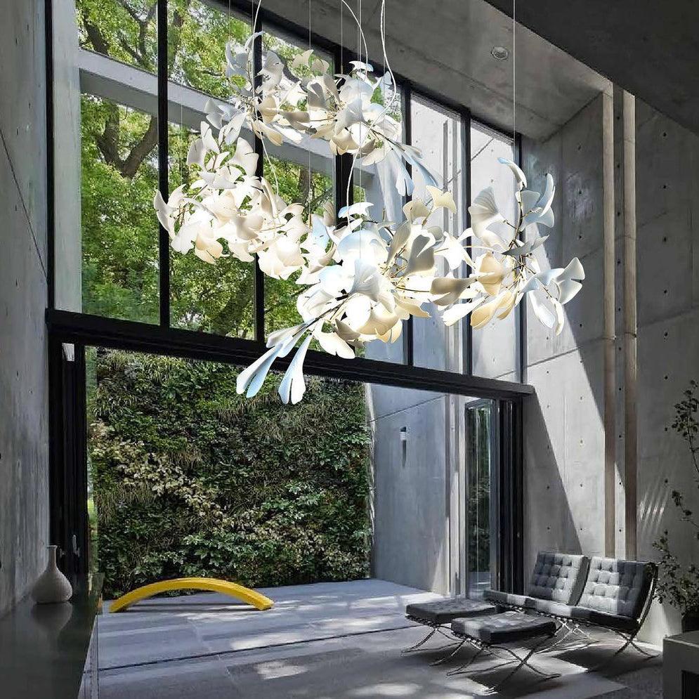The Clérachic gingko linear chandelier lit beside tall windows in a concrete-walled living space.