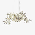 Clérachic gingko chandelier on white, ceramic leaves clustered along a gold branch.