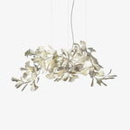 Clérachic gingko chandelier on white, ceramic leaves clustered along a gold branch.