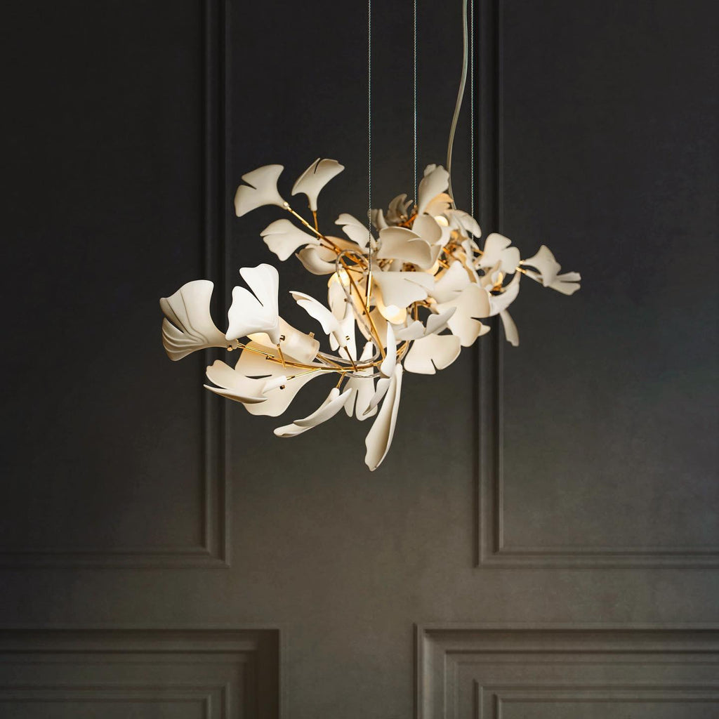 The Clérachic gingko chandelier lit against dark panelled doors, its leaves glowing warm.