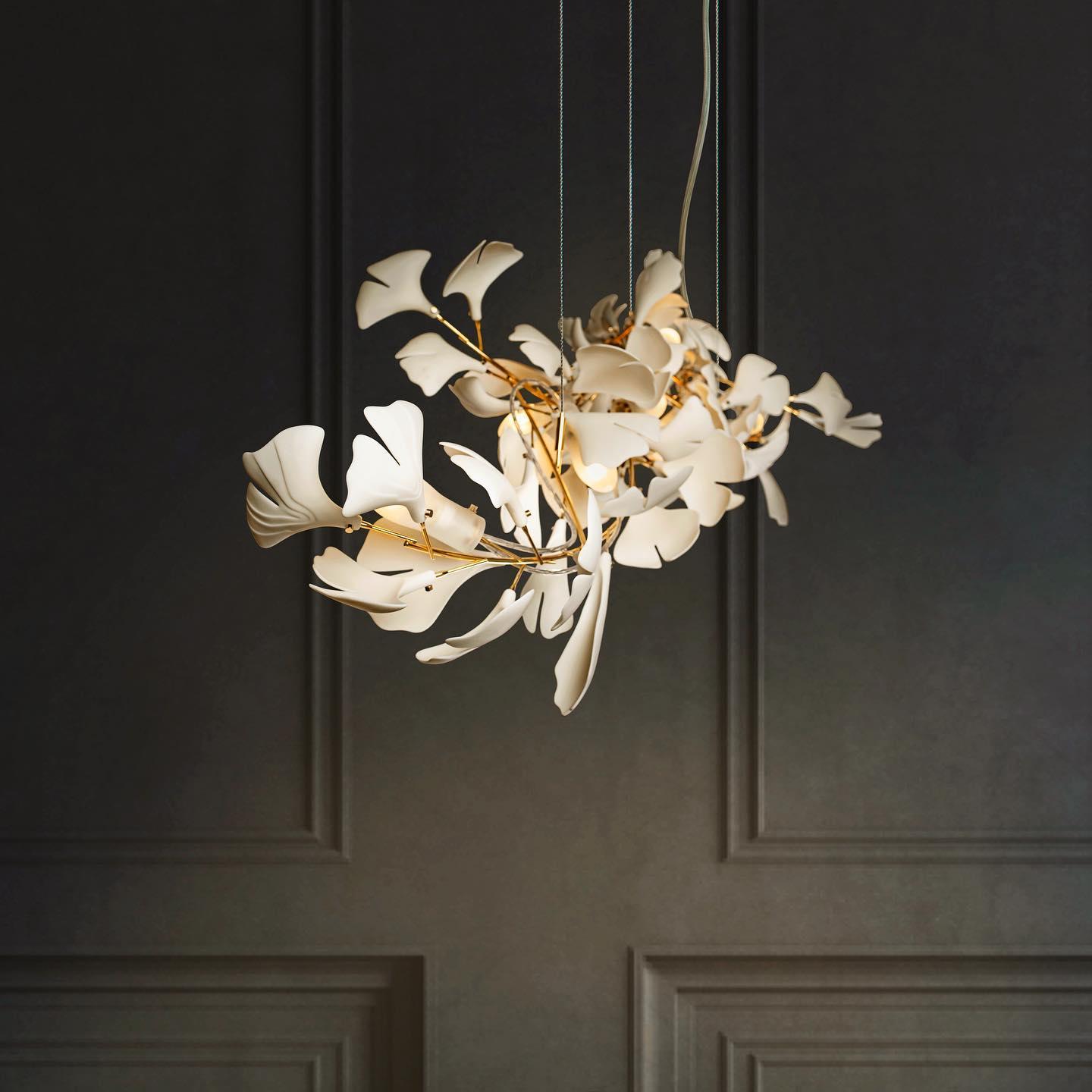 The Clérachic gingko chandelier lit against dark panelled doors, its leaves glowing warm.