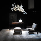 The Clérachic gingko chandelier lit above a writing desk and chair in a dark room.