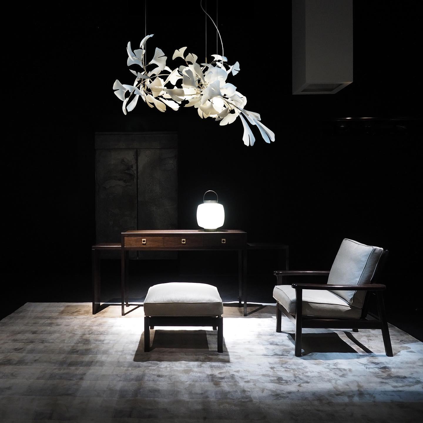 The Clérachic gingko chandelier lit above a writing desk and chair in a dark room.