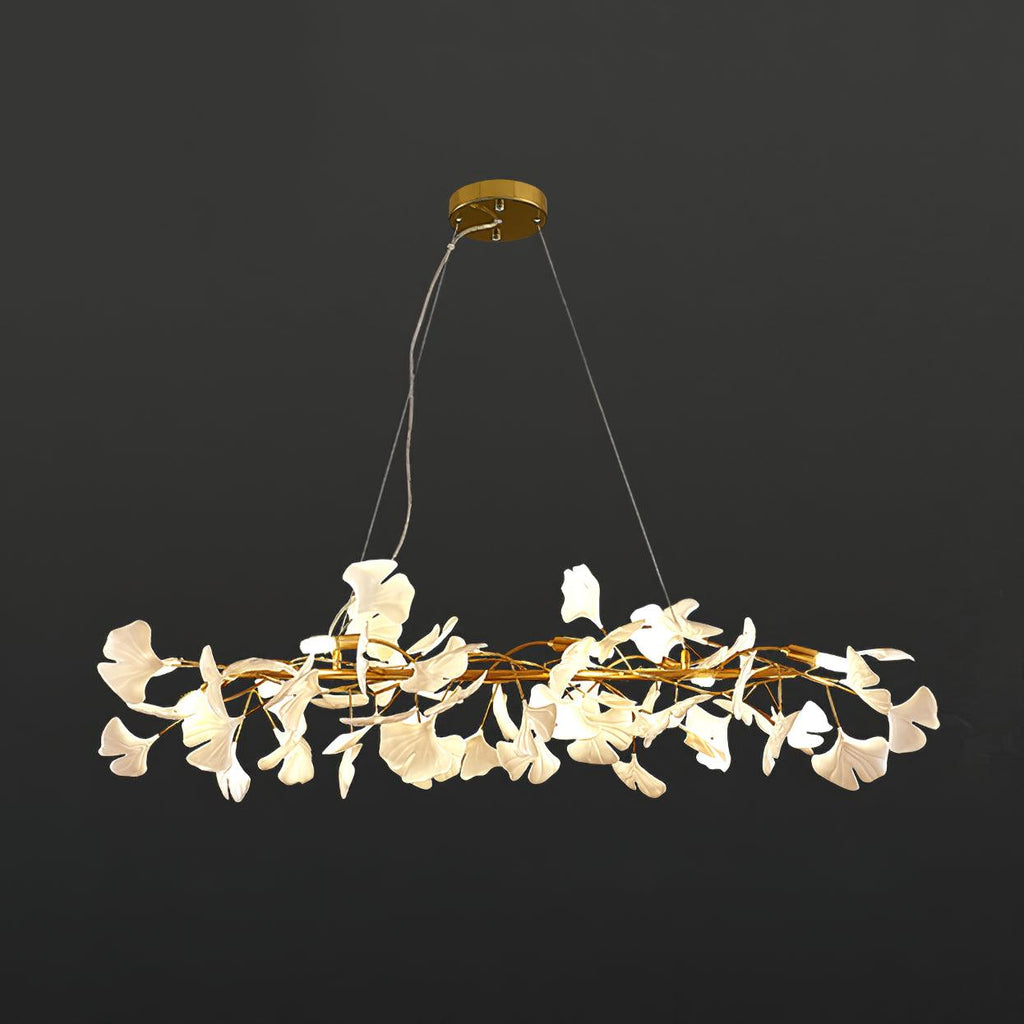 Clérachic gingko ring chandelier lit against charcoal, white leaves circling a gold frame.