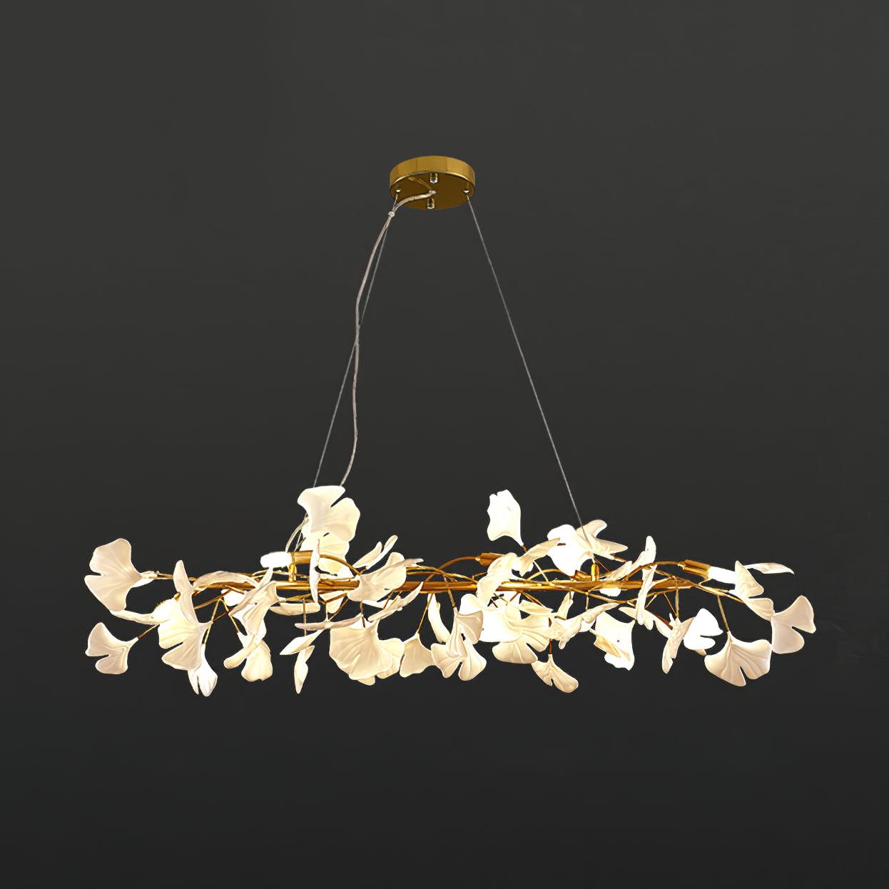 Clérachic gingko ring chandelier lit against charcoal, white leaves circling a gold frame.