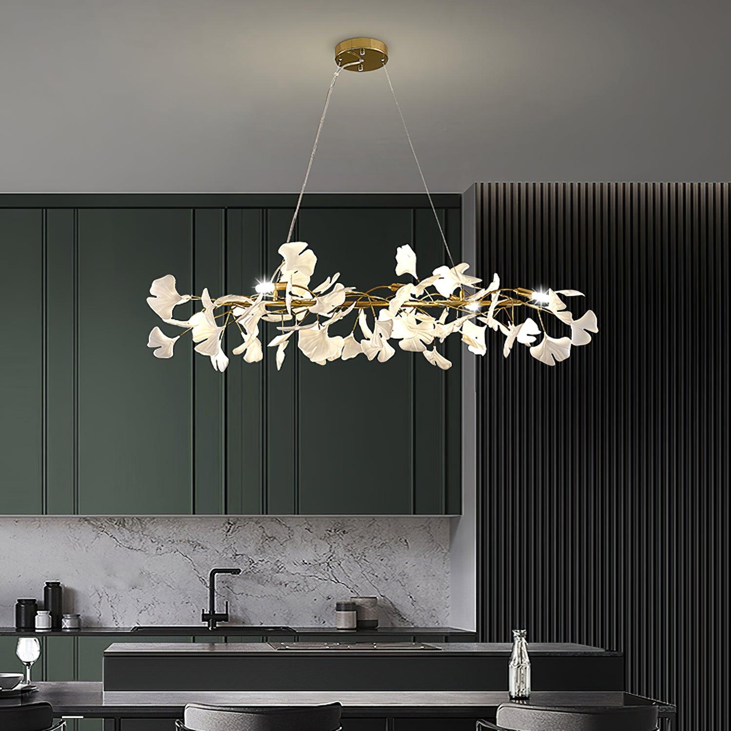 The Clérachic gingko ring chandelier lit above a kitchen island with green cabinetry.