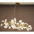 The Clérachic gingko ring chandelier lit in a warm-toned room, gold arms carrying white leaves.