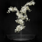 Clérachic gingko chandelier against black, porcelain leaves massed along a branching frame.