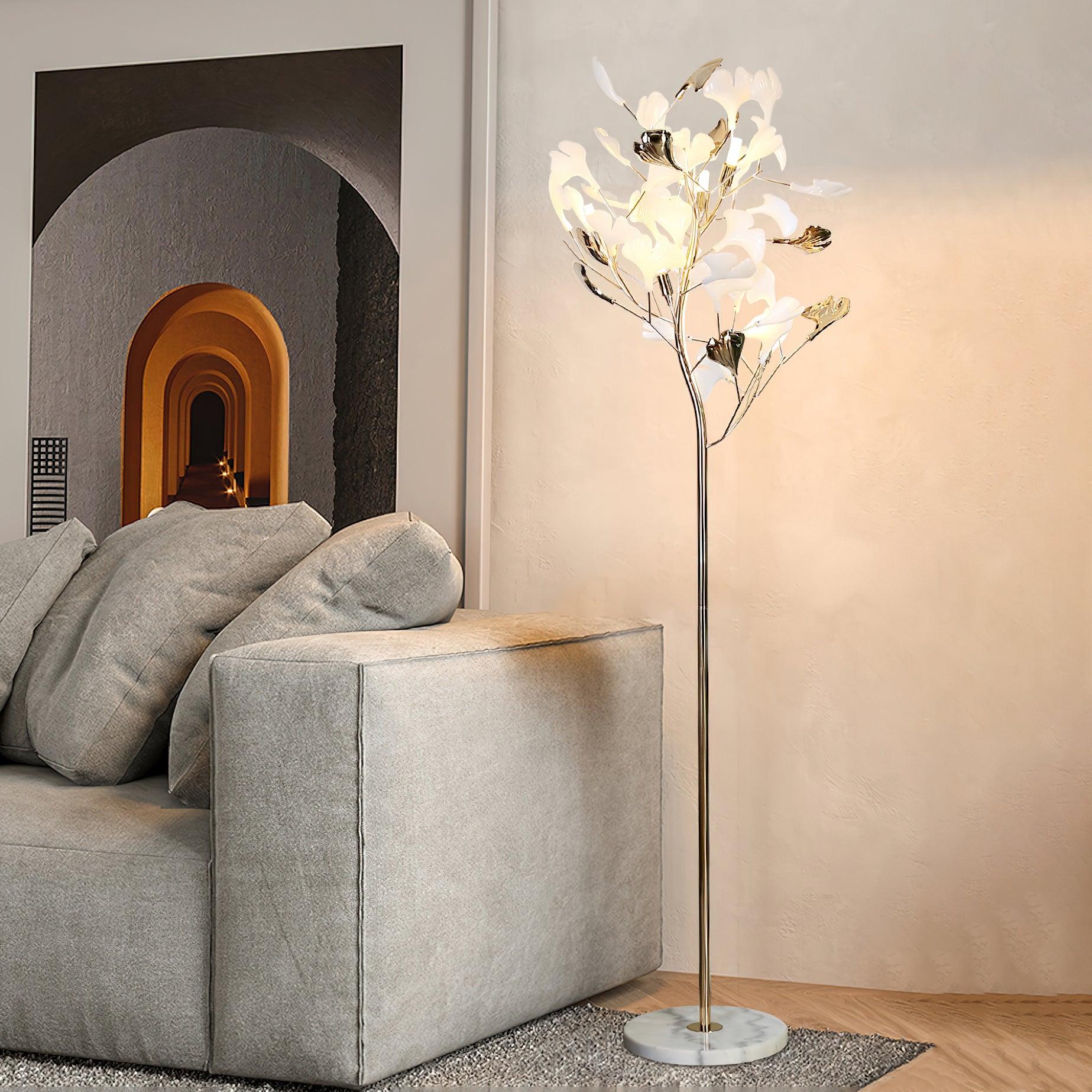 The Clérachic gingko floor lamp lit beside a grey sofa in a warm-toned living room.
