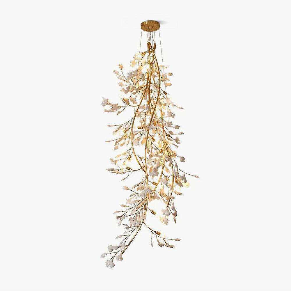 Clérachic gingko cascade chandelier lit against pale grey, gold branches trailing white ceramic leaves.