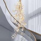 The Clérachic gingko cascade chandelier hanging beside a curved staircase in a bright double-height hall.