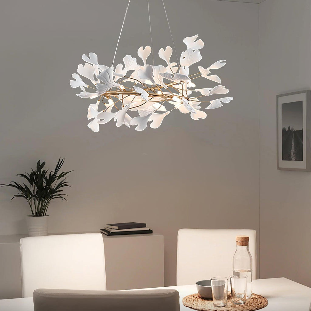 Clérachic gingko chandelier lit above a dining table beside a potted palm and framed print.