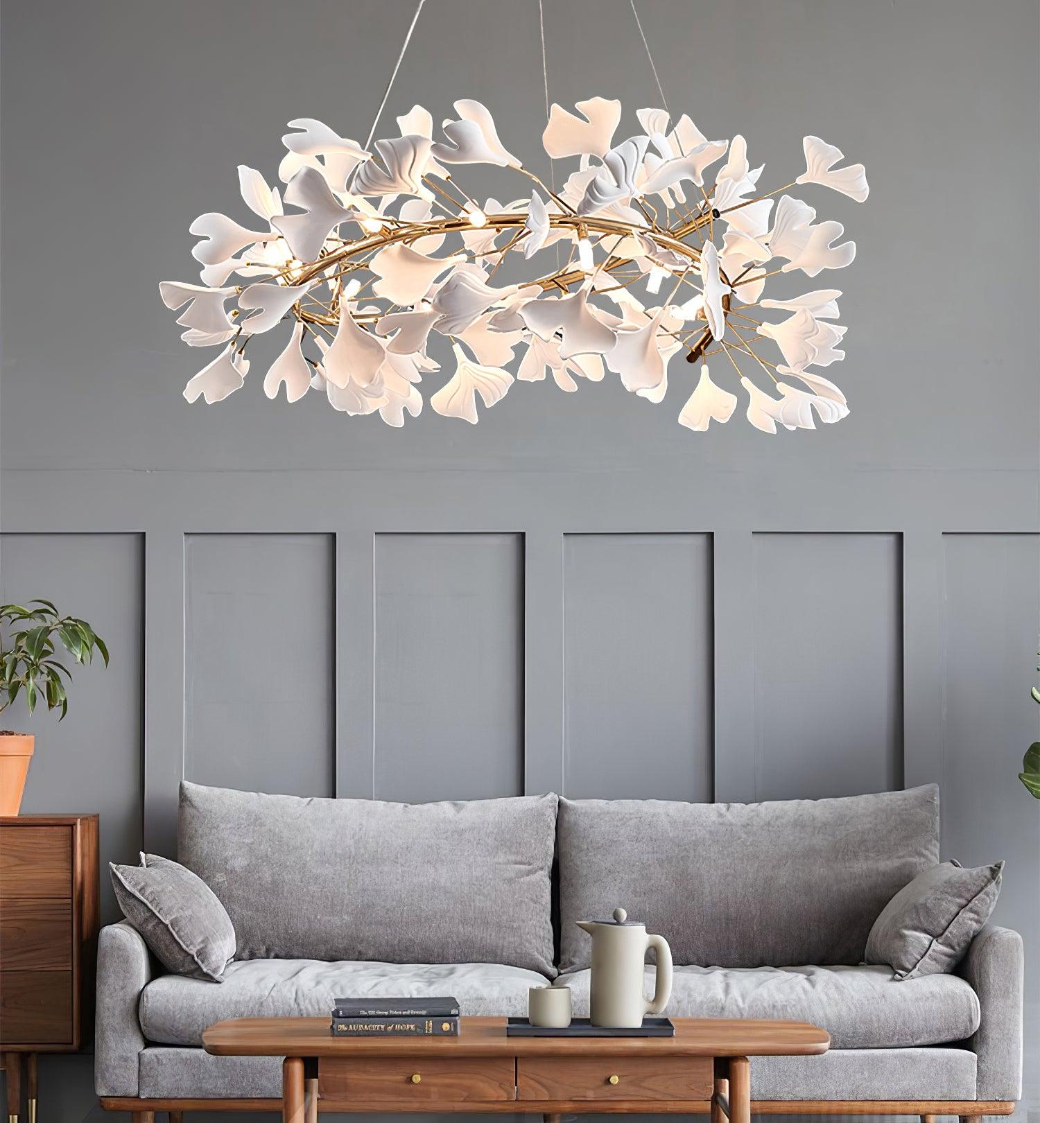 The Clérachic gingko chandelier lit above a grey sofa against panelled walls.