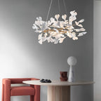 Clérachic gingko chandelier lit over a round travertine table with a red armchair alongside.