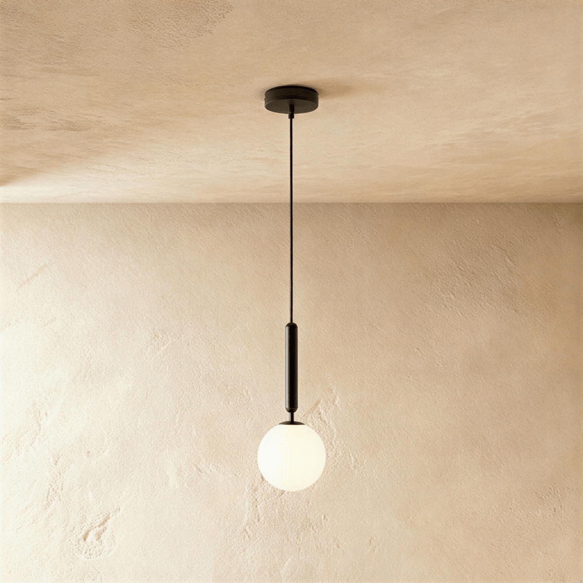 Clérachic single pendant with a milk white glass globe on a slim black rod and cord, hung against a limewashed wall.