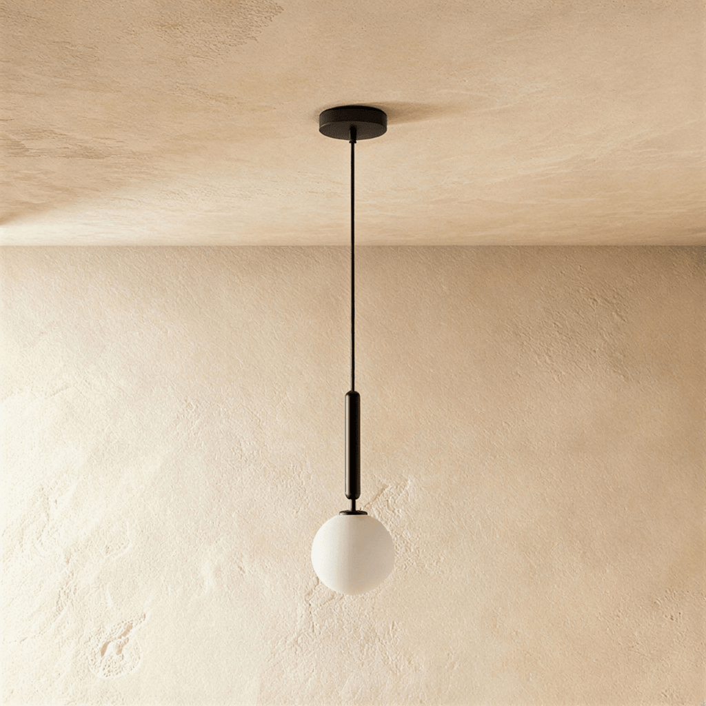 Clérachic single pendant, a milk white glass globe below a slim black cylinder and cord, on a plaster-toned wall.