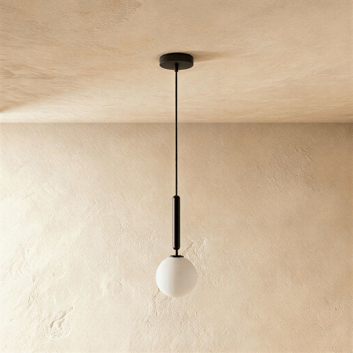 Clérachic single pendant, a milk white glass globe below a slim black cylinder and cord, on a plaster-toned wall.