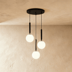Clérachic three-head pendant on a round black canopy, with milk white glass globes hung at three staggered heights.
